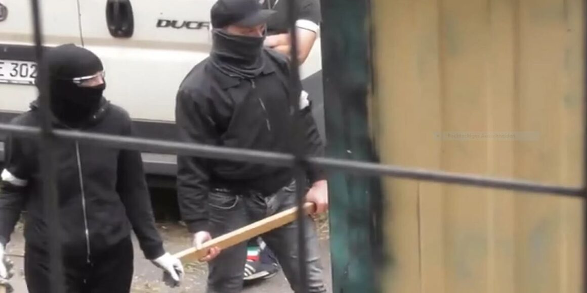 Vermummte Menschen mit Holzlatten