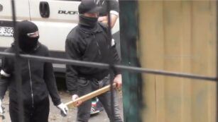 Vermummte Menschen mit Holzlatten