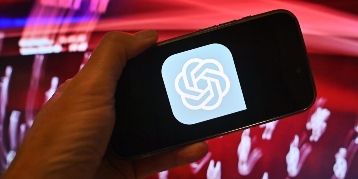 Hand zeigt ein Smartphone mit dem ChatGPT Logo vor rotem Hintergrund